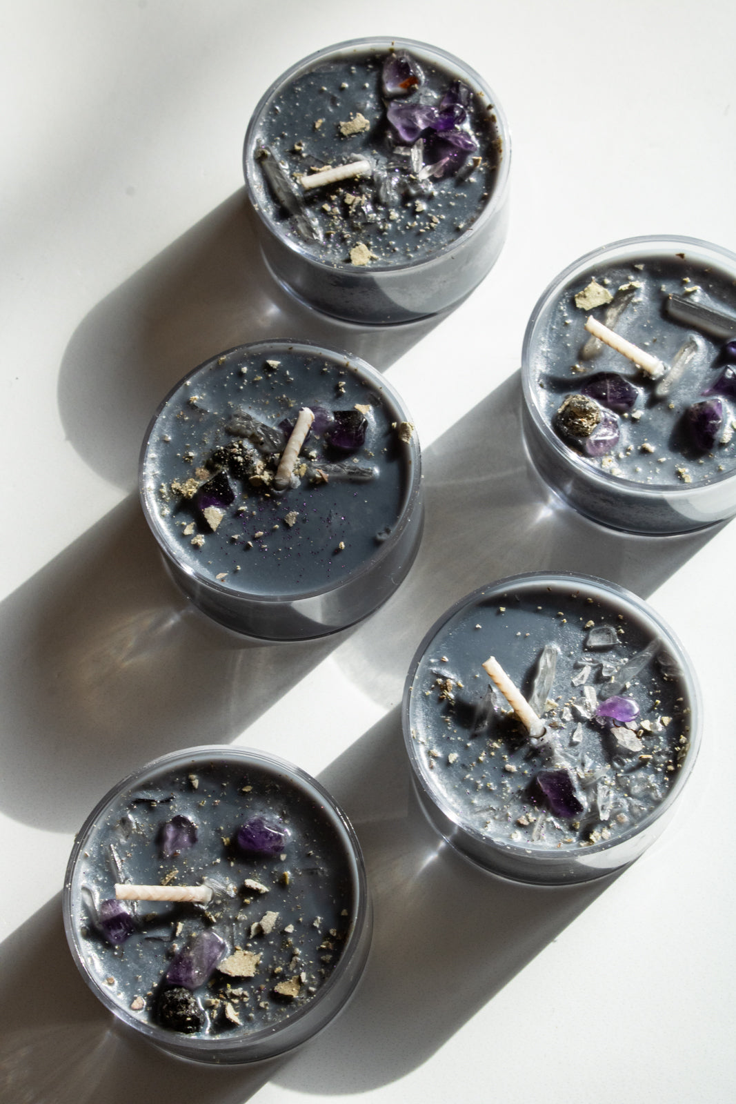 black tea light candles topped with dried herbs and crystals for protection