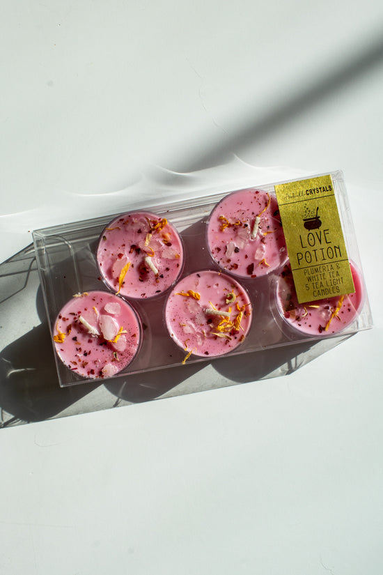 pink tea light candles topped with flower petals and crystals to attract love